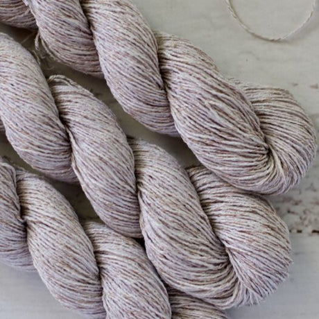 Two skeins of beige yarn on a light wooden surface