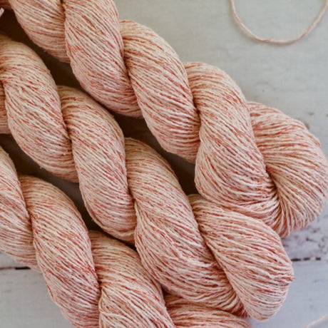 Two skeins of pink yarn on a light wooden surface