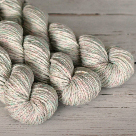 Gray and pink yarn skeins on a wooden surface