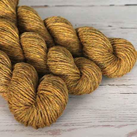 Three skeins of gold yarn on a wooden surface