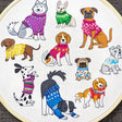 Embroidery hoop with embroidered dogs wearing colorful sweaters on a white background