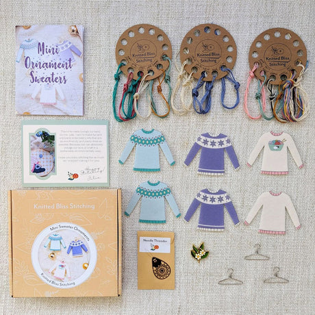 Knitted Mini Ornament Sweaters kit with packaging and materials on a textured surface