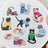 Embroidery hoop with embroidered cats wearing colorful sweaters on a white background.