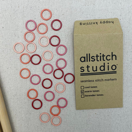 Allstitch Studio stitch markers with a sample of colored rings on fabric.