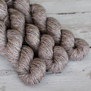 Three skeins of brown yarn on a wooden surface