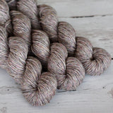 Three skeins of brown yarn on a wooden surface